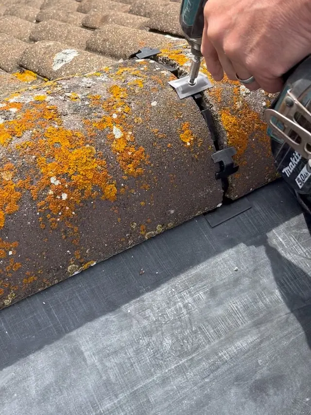 Worn and moss covered ridge tiles before being replaced