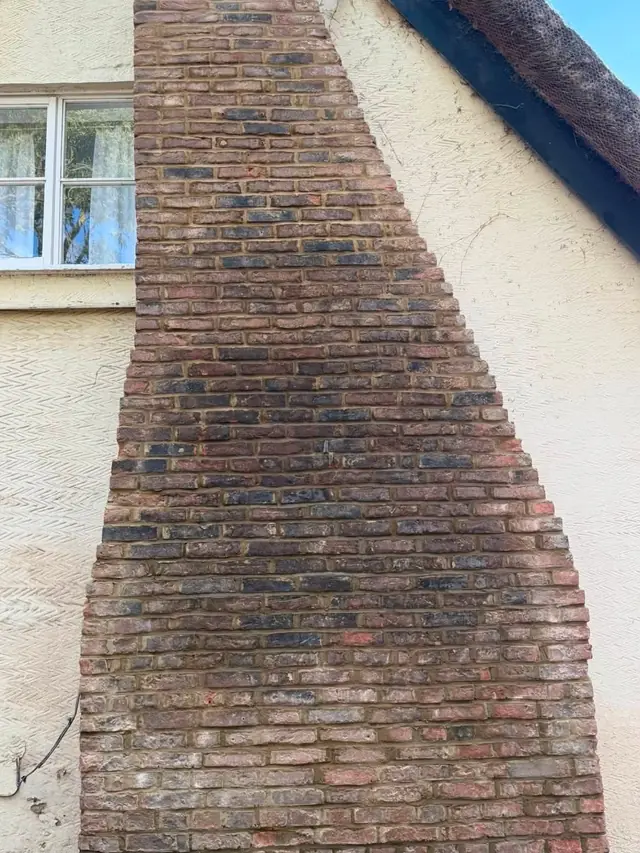 Brick chimney breast on a cream rendered wall with a ladder in place