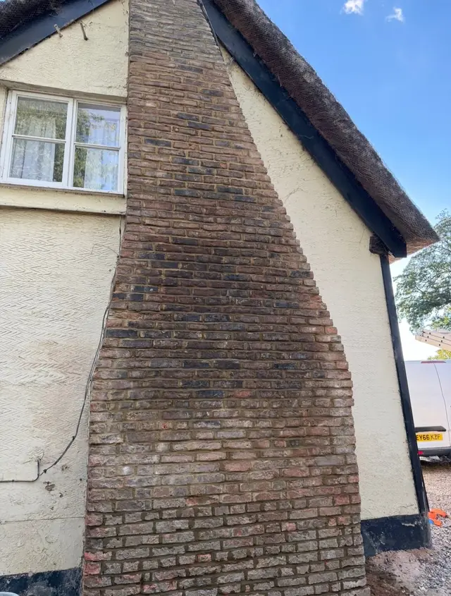 Chimney breast running up a cream rendered gable beside a window