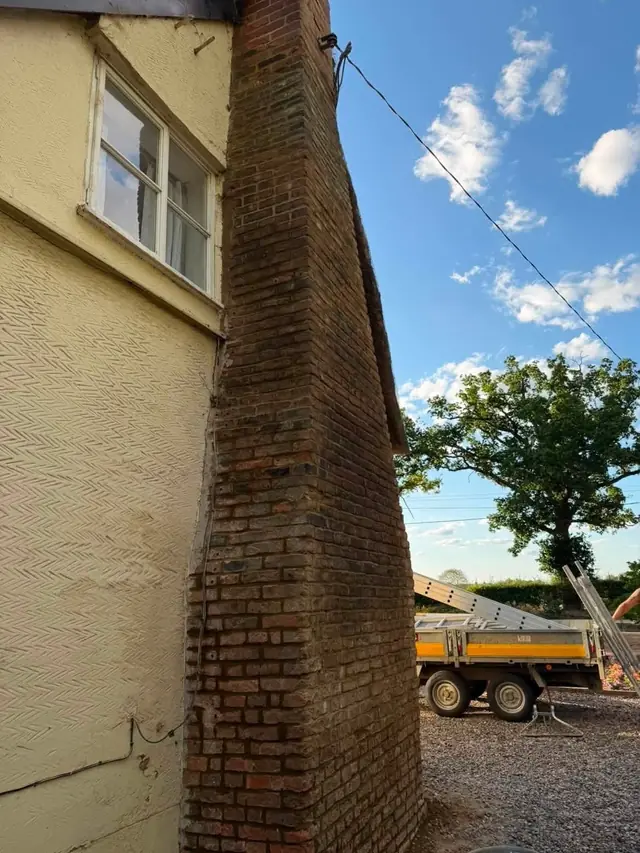 Tall chimney stack on a rendered gable with the tipper lorry on site
