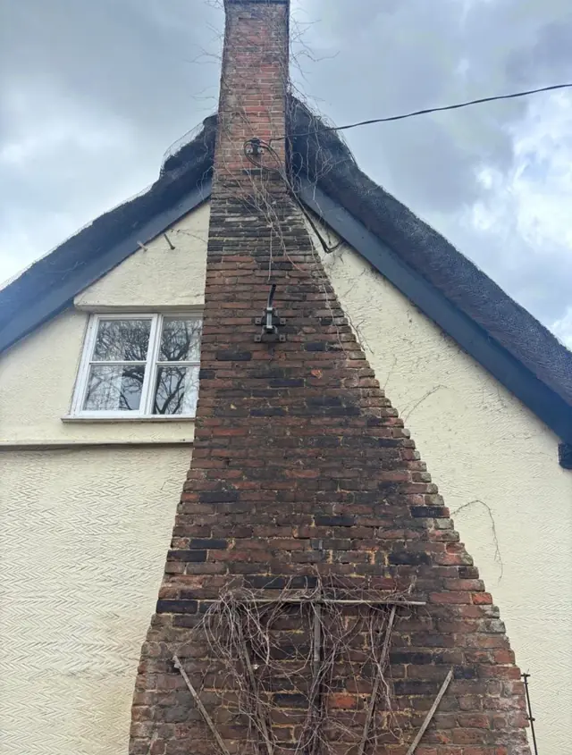 Brick chimney breast on the white rendered gable of a period property