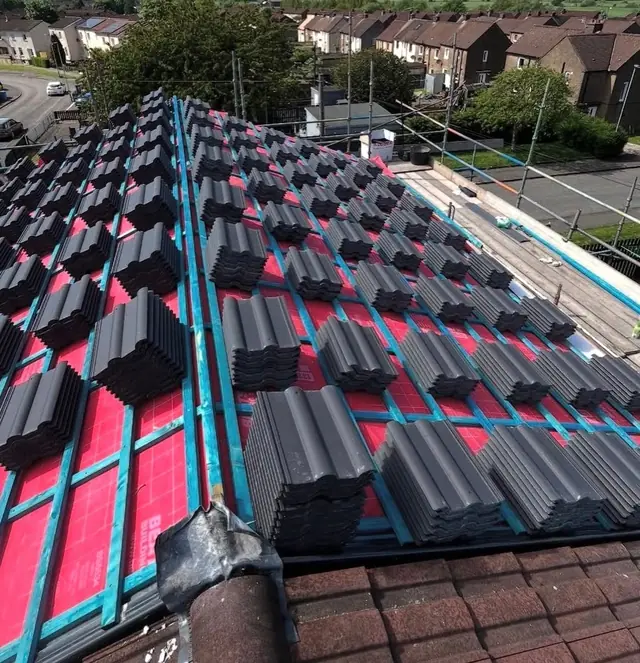 New roof tiles being laid over red breathable underlay