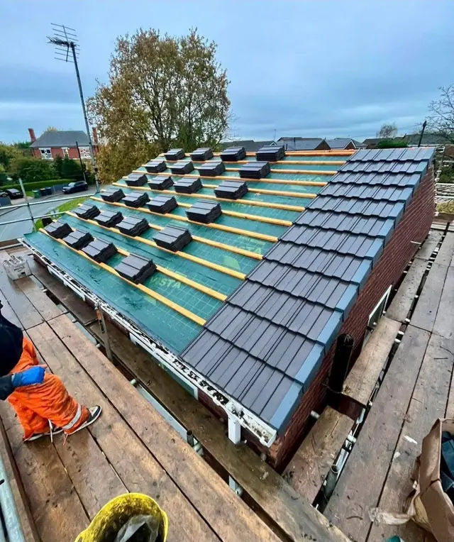 Grey roof tiles being laid over new breathable membrane