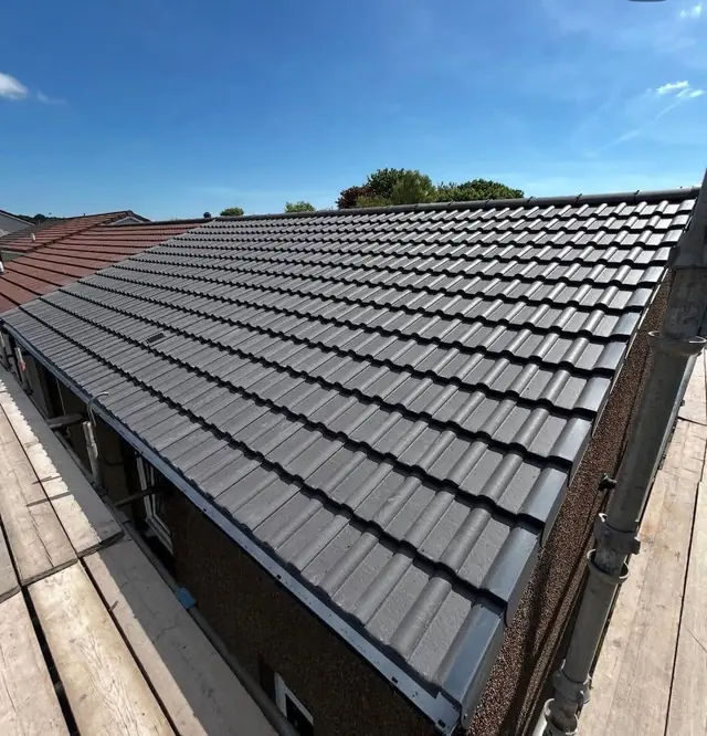 Finished anthracite tiled roof with the ridge running away towards the horizon