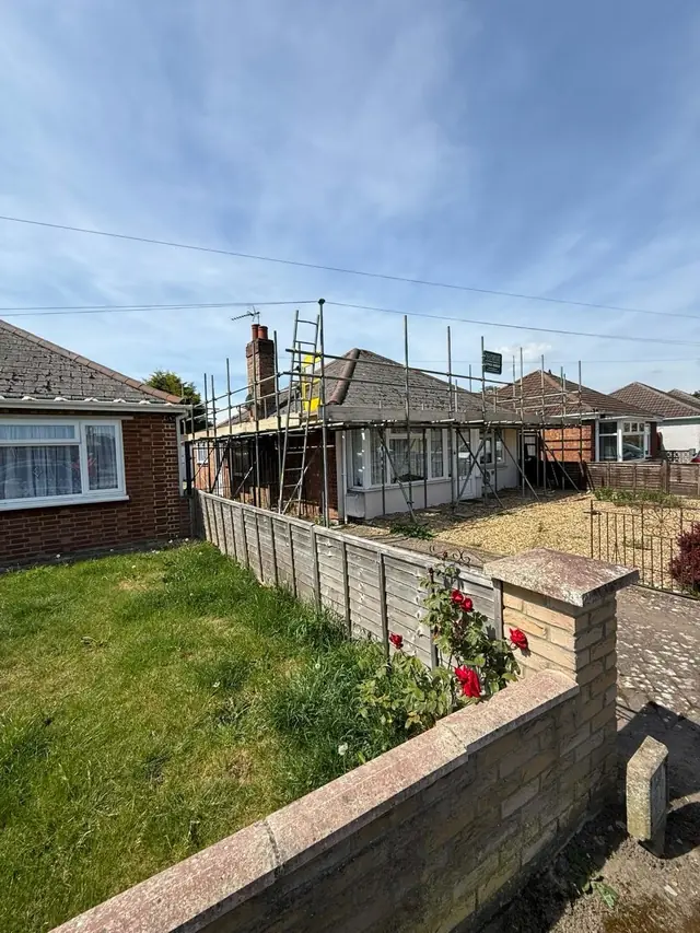 Bungalow with scaffolding up and a clear blue sky
