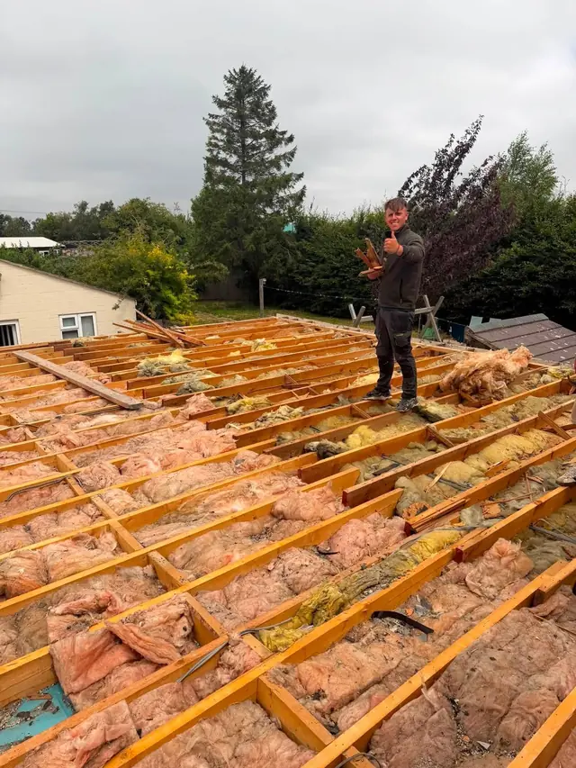 Stripped roof with new battens and underlay, roofer at work