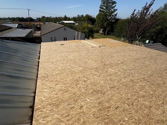 Stripped roof deck with a roofer working on a bungalow