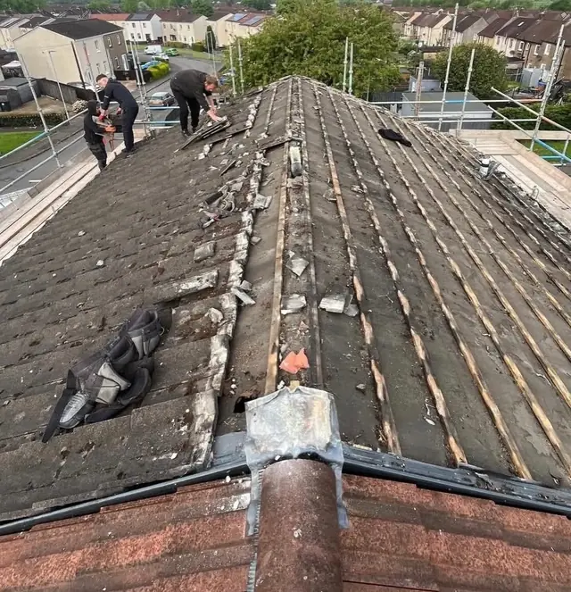 Roofers stripping a roof with the town rooftops behind