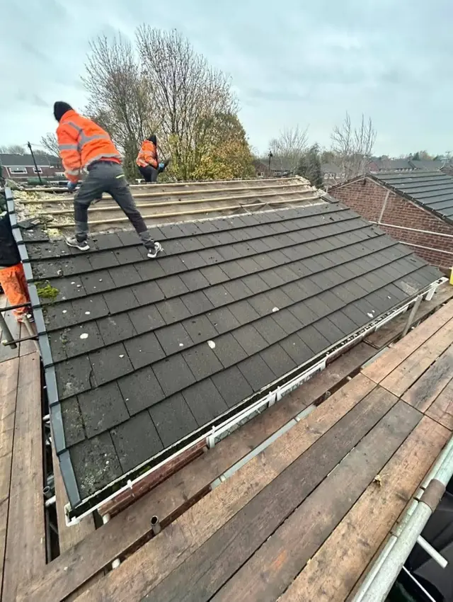 Roofer in hi vis fitting new rafters during a full re-roof