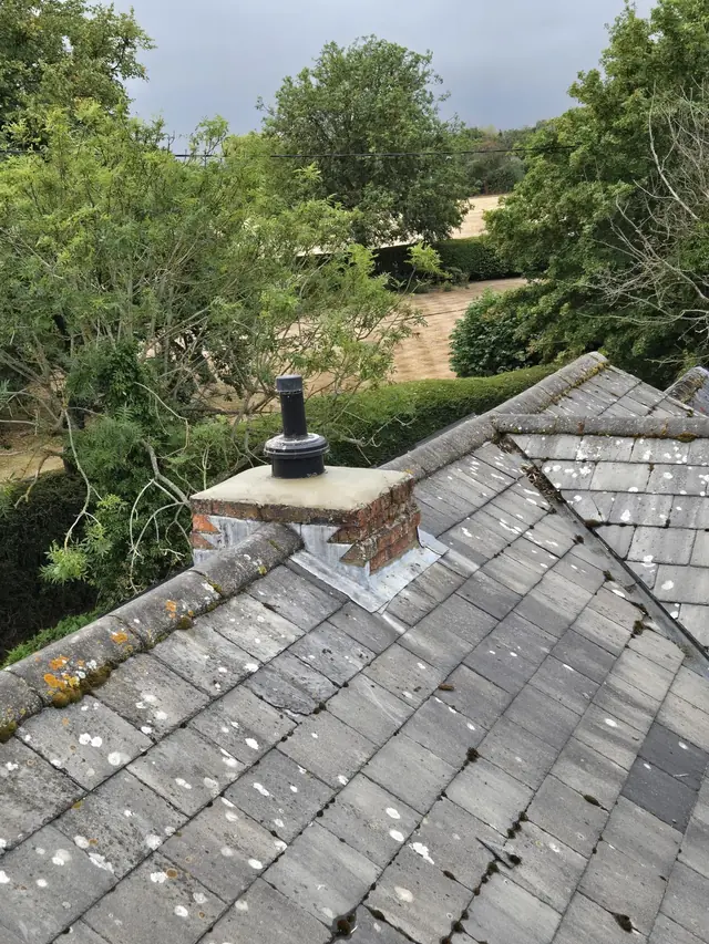 Slate roof and chimney stack with trees behind