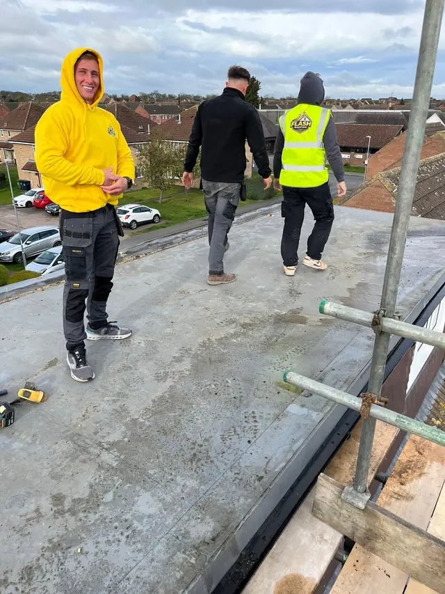 Three Flash Roofing roofers working together on a scaffolded roof